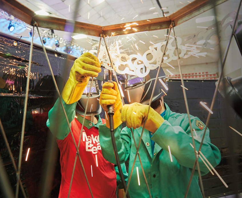 Participants weld steel numbers representing digits of Pi during a campus fabrication and crafts showcase.