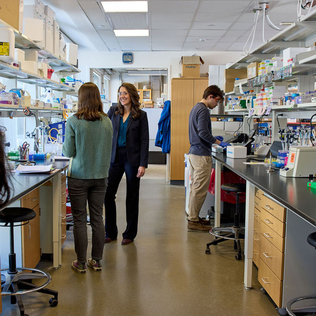 Chemical engineer Katie Galloway stands in her lab talking to a student.